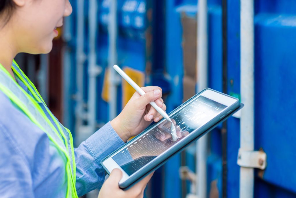 A logistics specialist checking data on a digital tablet to eliminate industrial tracking errors on the field.