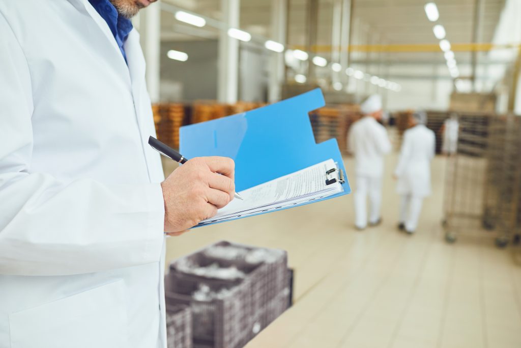 A plant supervisor manually recording data on a clipboard, representing manufacturing reporting bottlenecks in the production chain.
