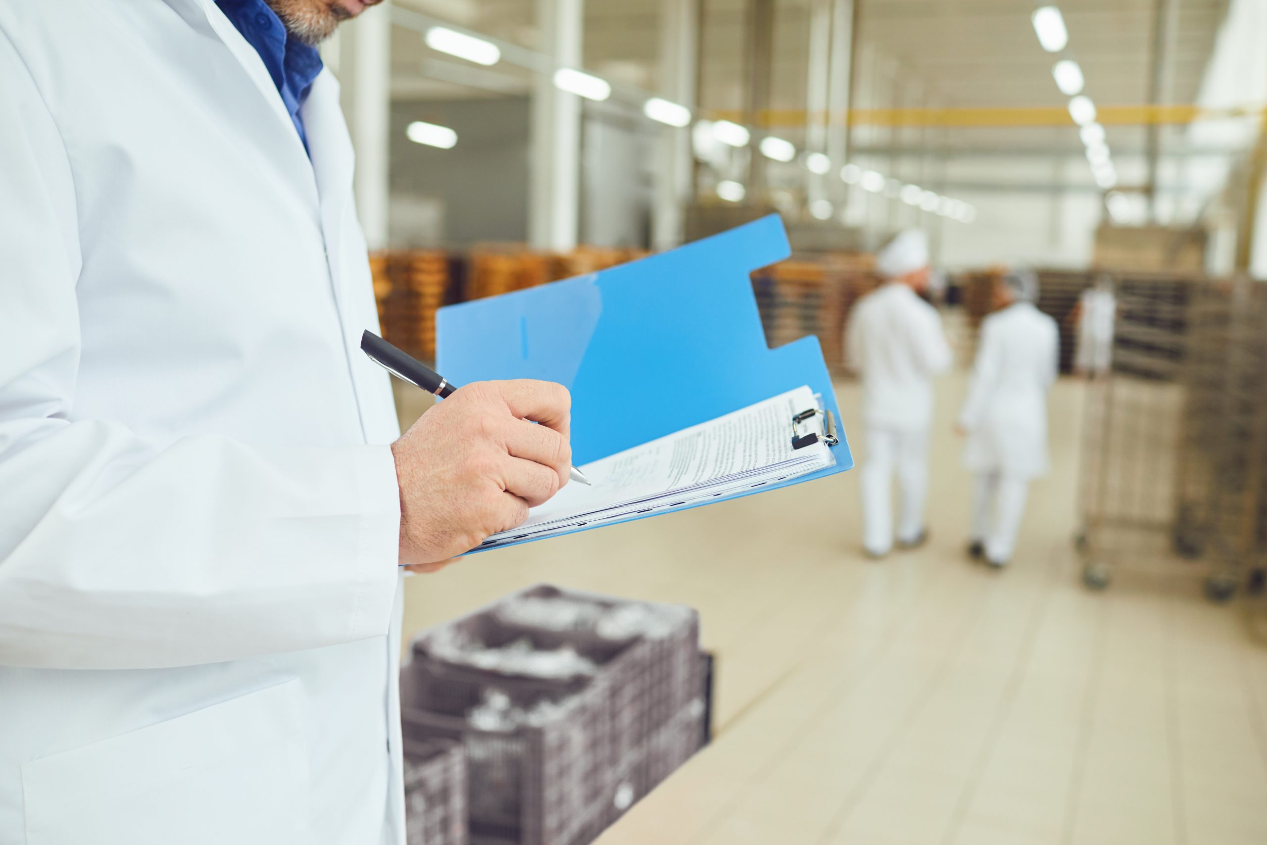 A plant supervisor manually recording data on a clipboard, representing manufacturing reporting bottlenecks in the production chain.