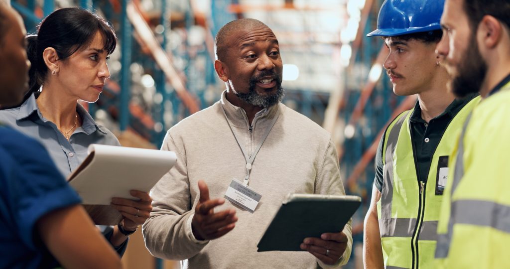 Cross-departmental team reviewing shared operational data together in warehouse
