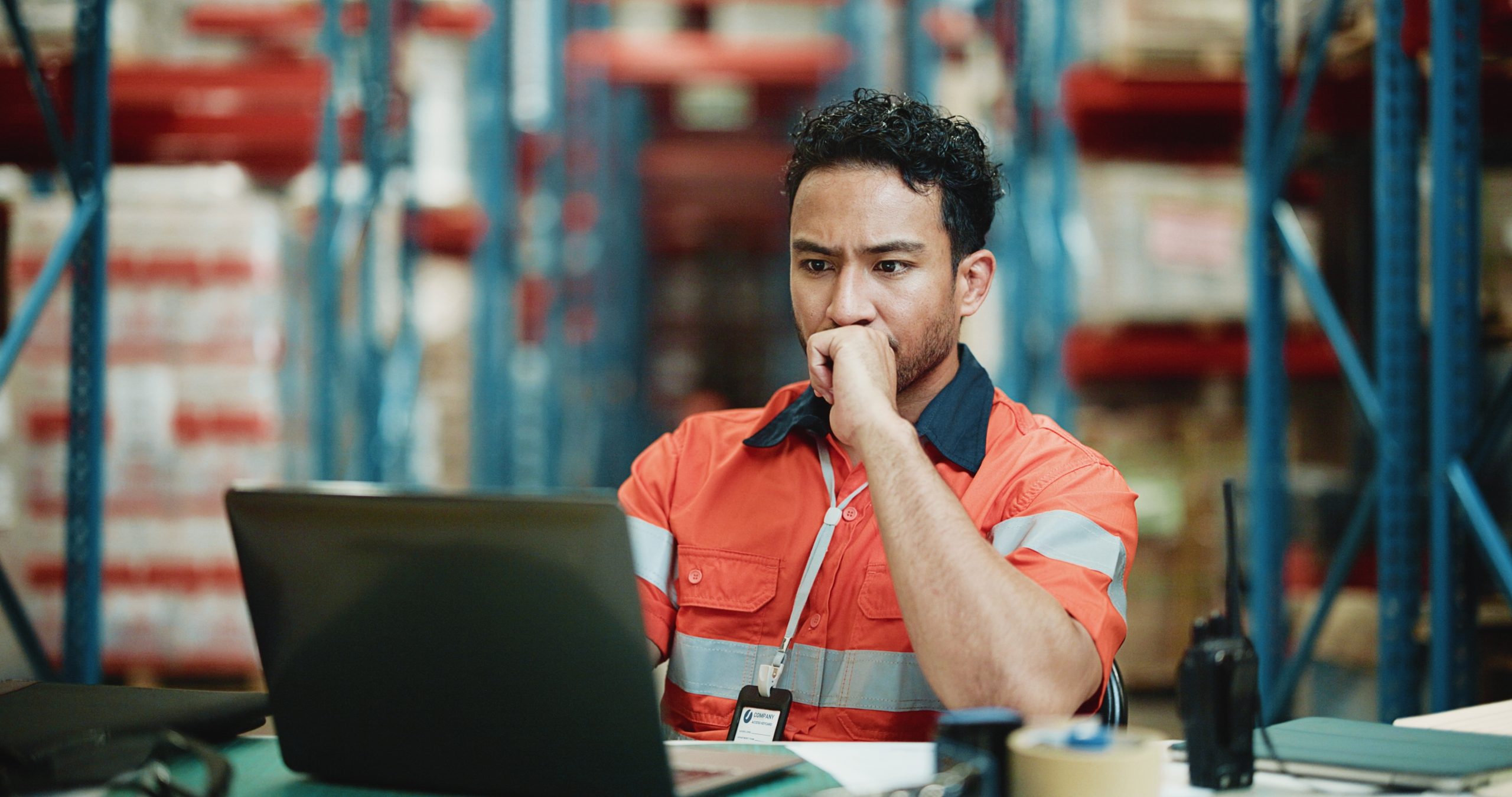 Operations manager reviewing delayed procurement workflow on laptop in warehouse