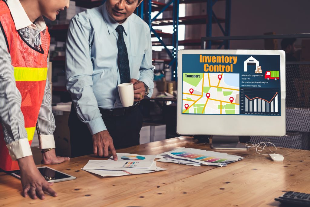 A close-up of a tablet displaying an inventory control dashboard with charts and maps for managing multi-location inventory control across several warehouses.